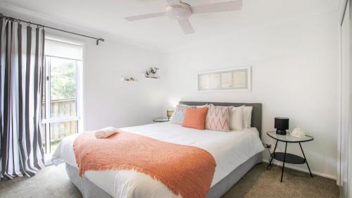 a bedroom with a bed with an orange blanket and a window at Stones Throw To Copacabana Beach in Copacabana