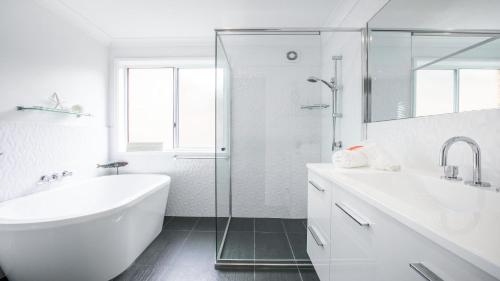 a white bathroom with a tub and a sink at Stones Throw To Copacabana Beach in Copacabana