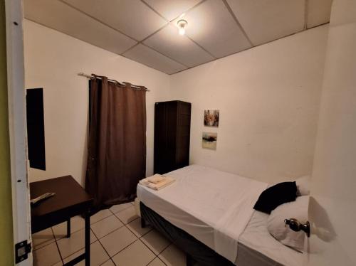 a small bedroom with a bed and a desk at Casa Las Azucenas in Sonsonate