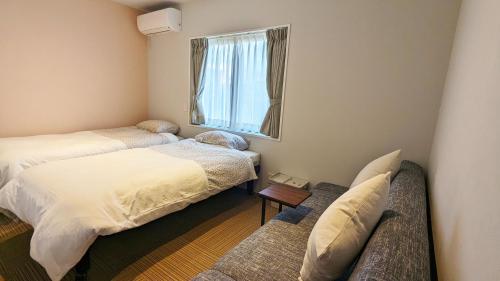 Habitación con 2 camas, sofá y ventana en MAHHO TERRACE MIYAKO en Isla Miyako