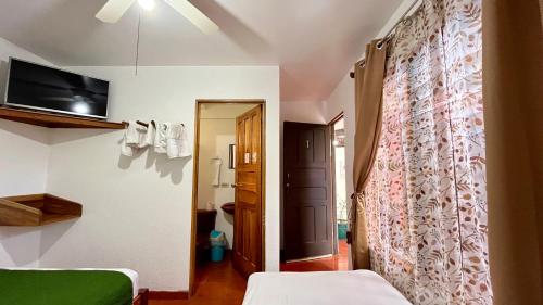 a room with two beds and a wall with a curtain at Hostal Nuevo Arenal downtown, private rooms with bathroom in Nuevo Arenal