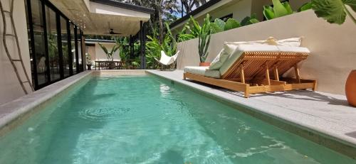 a swimming pool with a couch and a chair next to a house at Walk to the Beach! House in private compound! Pool, Kitchen, AC, Wi-Fi in Mal País