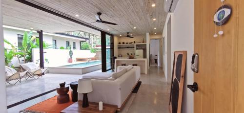 a living room with a white couch and a table at Walk to the Beach! House in private compound! Pool, Kitchen, AC, Wi-Fi in Mal País