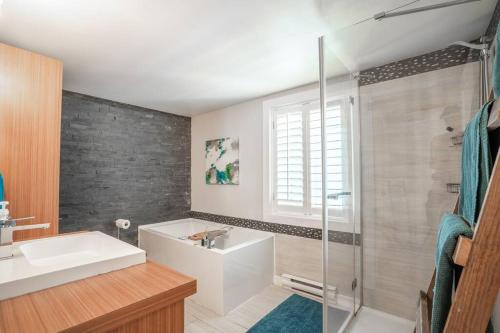 a bathroom with a tub and a sink and a shower at Rustic & Modern Chalet 32 Acre of Land in Saint-Paulin