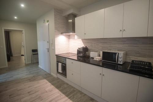 eine Küche mit weißen Schränken und einer schwarzen Arbeitsplatte in der Unterkunft Vista do Baixio in Vila Franca do Campo