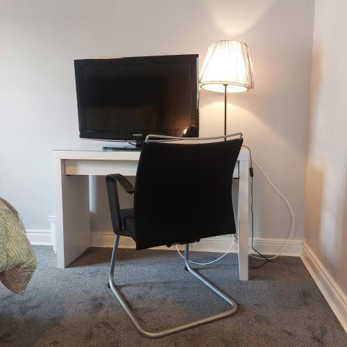 a chair in front of a desk with a television at Lawnbrook Town House in Belfast