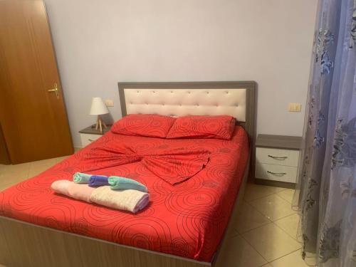 a bed with red sheets and two towels on it at Guest House Fier in Fier