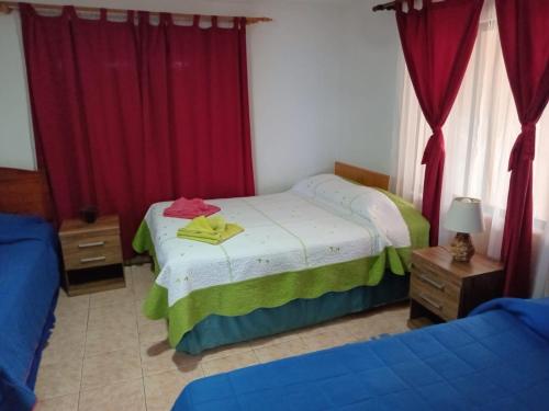 a bedroom with two beds and red curtains at Cabañas & Hostal Tojika in Hanga Roa