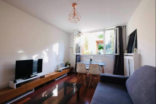 ein Wohnzimmer mit einem Sofa, einem TV und einem Tisch in der Unterkunft Lovely spacious nest in Ivry in Ivry-sur-Seine