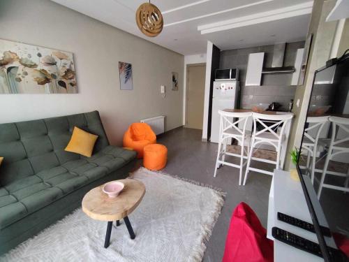 a living room with a green couch and a table at Coquette Appartement in Boumhel El Bassatine