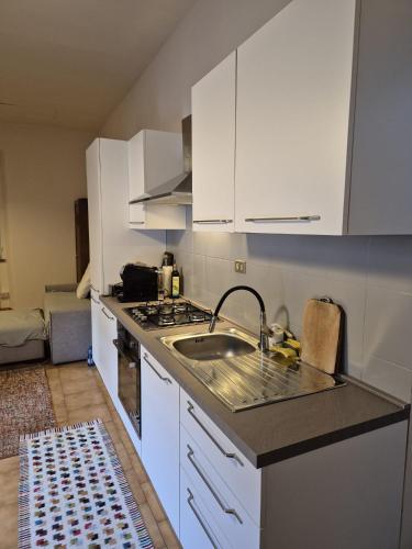 a kitchen with white cabinets and a sink at villetta con giardino privato in Cremia