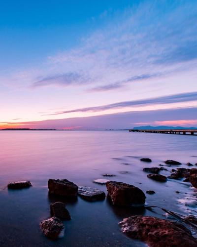a sunset over the water with rocks and a pier at Il Canto Di Iside in Marsala