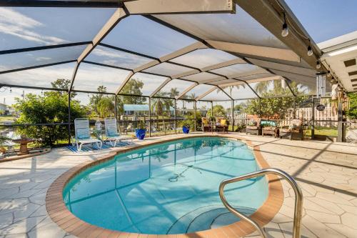a swimming pool with an umbrella and chairs around it at Port Charlotte Paradise with Private Outdoor Oasis! in Port Charlotte