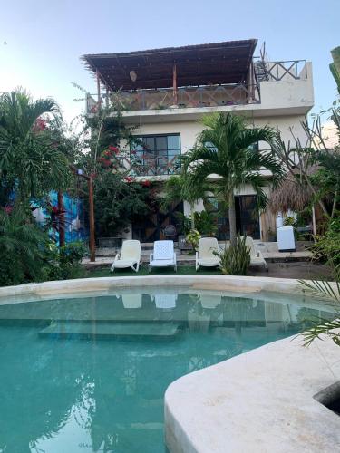 a swimming pool with two chairs and a building at Casa Delfín Tulum in Macario Gomez