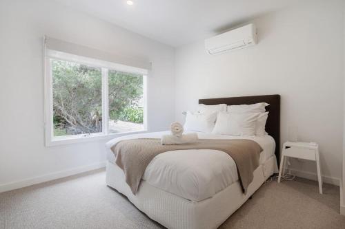 Un dormitorio blanco con una cama con un osito de peluche. en In the Heart of Flinders - A Beachside Family Escape, en Flinders