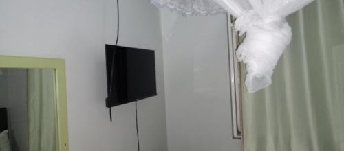 TV de pantalla plana en una pared junto a un espejo en Pals Inn, en Busia