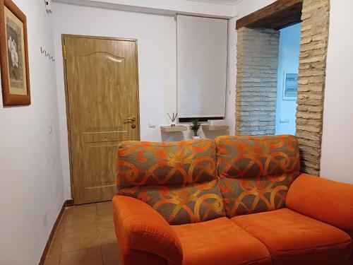 un sofá naranja en una sala de estar con puerta en La casita Ronda, en Ronda