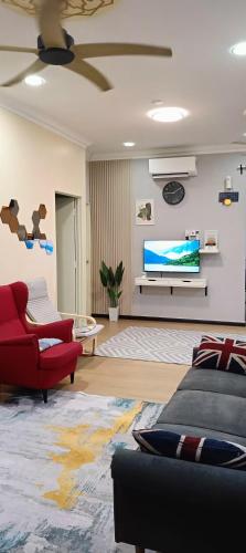 a living room with a tv and a red couch at DH Merlimau Homestay in Merlimau