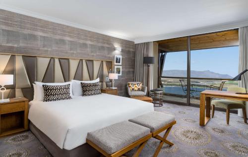 a bedroom with a large bed and a large window at Arabella Hotel, Golf and Spa in Kleinmond