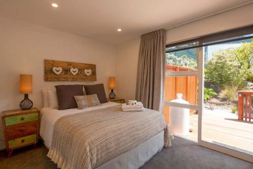 a bedroom with a bed and a sliding glass door at Hillside Villa 3- Walk To Town- AC- Free Parking in Queenstown