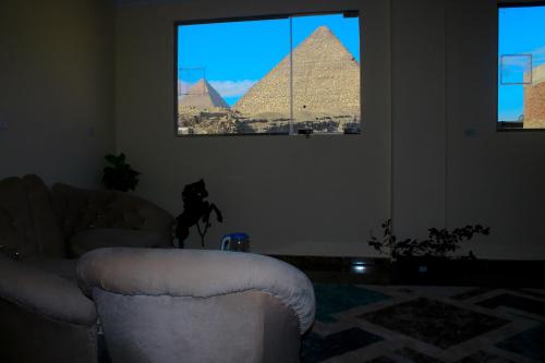 a living room with two chairs and the pyramids at Energy Of Pyramid Hotel in Cairo