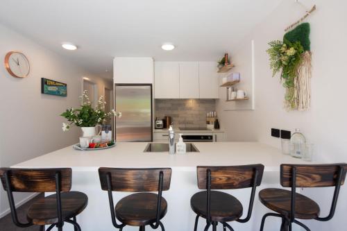 a kitchen with a white counter and wooden chairs at Hillside Villa 1- Walk To Town- AC- Free Parking in Queenstown