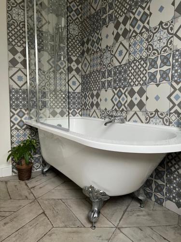 a white bath tub in a bathroom with tiles at Ilford Hidden Gem in Ilford