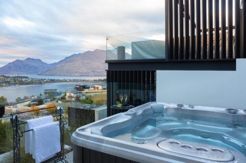 a bath tub on a balcony with a view of the water at Aurora Lodge- AC- Free Parking- Hot Tub- BBQ in Queenstown