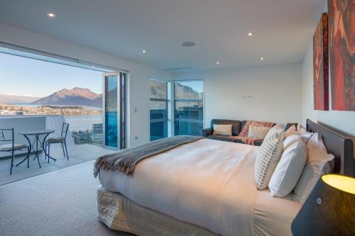 een slaapkamer met een bed en een balkon met uitzicht bij Aurora Lodge- AC- Free Parking- Hot Tub- BBQ in Queenstown