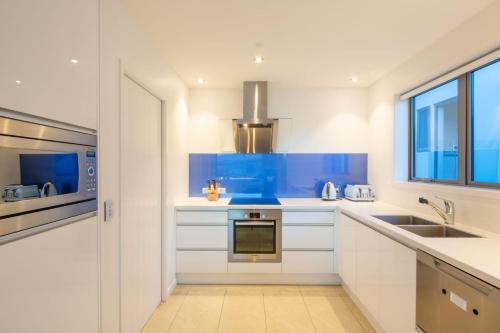 a kitchen with white cabinets and a blue counter top at Aurora Lodge- AC- Free Parking- Hot Tub- BBQ in Queenstown