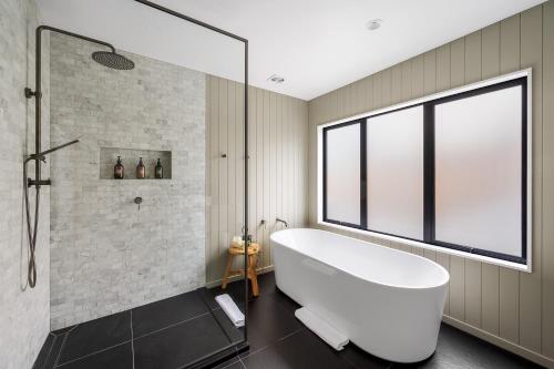 een badkamer met een groot wit bad en een raam bij Karearea- AC- Free Parking- BBQ- Hot Tub in Queenstown