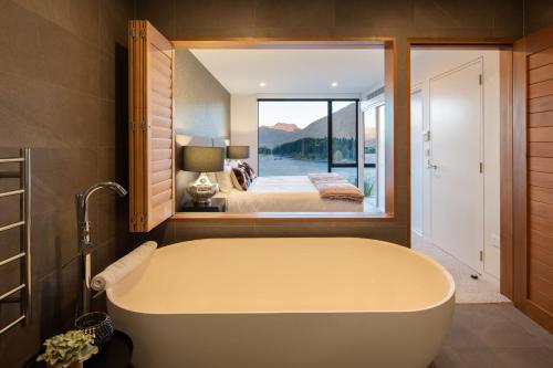 eine Badewanne in einem Schlafzimmer mit einem Bett und einem Fenster in der Unterkunft Lakehouse 1- Free Parking- Walk To Town- Air Con in Queenstown