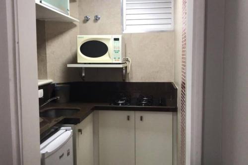 a small kitchen with a microwave and a sink at Flat mobiliado em Campinas - Ap 124 L Hirondelle in Campinas