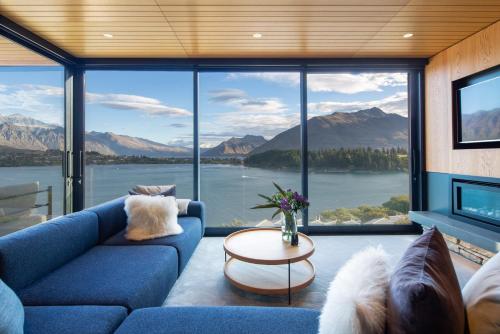 a living room with a blue couch and large windows at Lakehouse 2- Free Parking- Walk To Town- Air Con in Queenstown