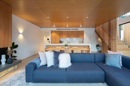a living room with a blue couch and a kitchen at Lakehouse 2- Free Parking- Walk To Town- Air Con in Queenstown
