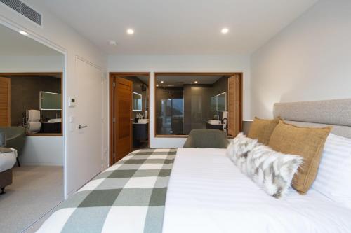 a bedroom with a large white bed and a living room at Lakehouse 3- Free Parking- Walk To Town- Air Con in Queenstown
