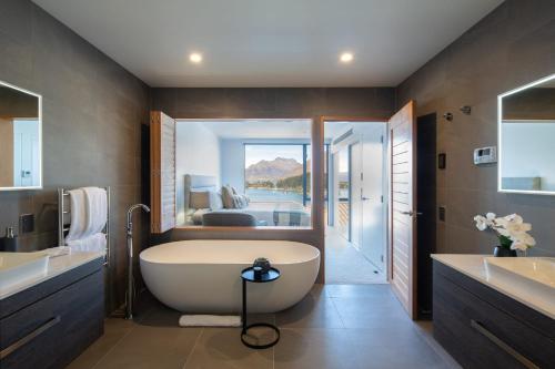 a bathroom with a large tub and a bedroom at Lakehouse 3- Free Parking- Walk To Town- Air Con in Queenstown