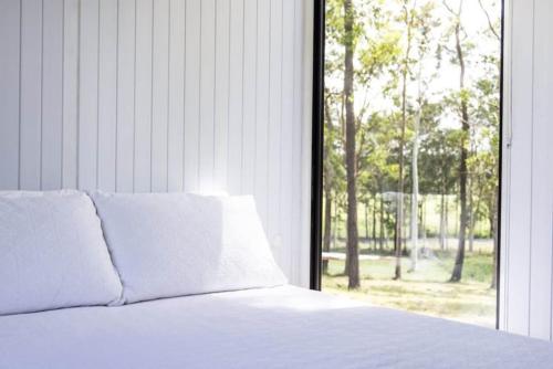 Bett mit weißen Kissen vor dem Fenster in der Unterkunft Country Escape in Wingham