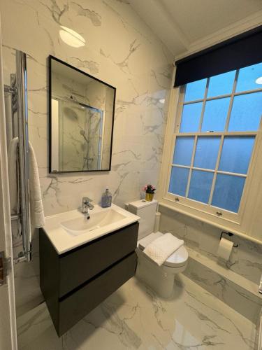 a bathroom with a sink and a toilet and a mirror at Camden Town Apartment in London