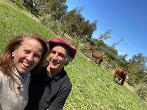 a man and a woman standing in a field with horses at La Alegría 