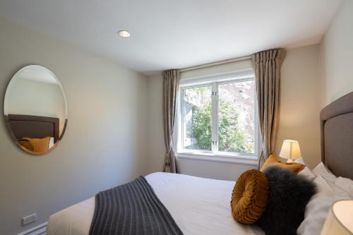 a bedroom with a bed with a mirror and a window at Manuka Lakeside Apt- Free Parking- Walk To Town in Queenstown