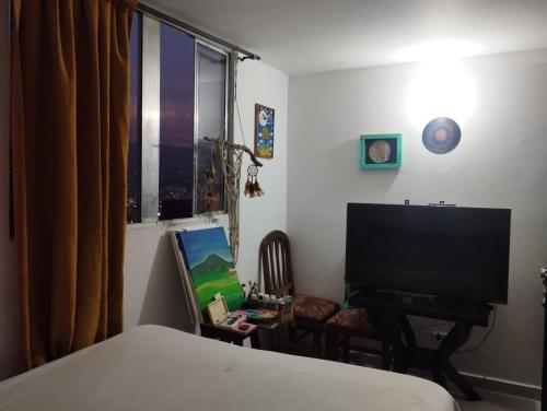 1 dormitorio con TV de pantalla plana y silla en Welcome to Medellin in our home, en Medellín