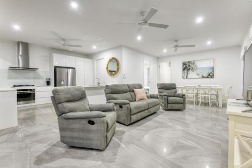 a living room with two chairs and a kitchen at Luxury Retreat on Mudlo, 4 bedroom home with pool in Port Douglas