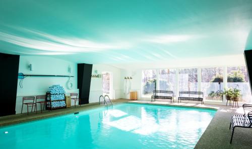 a large swimming pool with chairs and a large window at Tälta Lodge, a Bluebird by Lark in Stowe