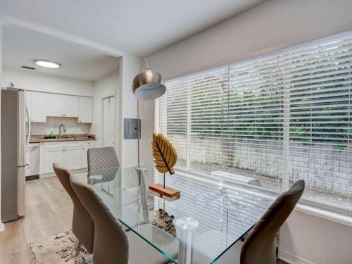 uma sala de jantar com uma mesa e cadeiras de vidro e uma janela em Miami Luxury 4 BD Home, Next to Wynwood & North Beach em North Miami