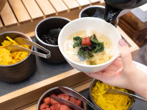 uma pessoa está segurando uma tigela de comida em Super Hotel Yamaguchi Yuda Onsen em Yamaguchi