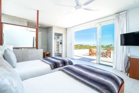 Habitación blanca con cama y balcón. en Beachside 3 Bedroom Villa with Pool and Resort Amenities - White Villas - v4 en Providenciales