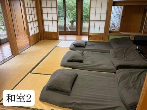 a room with four beds in a room with windows at さくらの宿Traditional Japanese house with cherry blossoms in Hasunuma