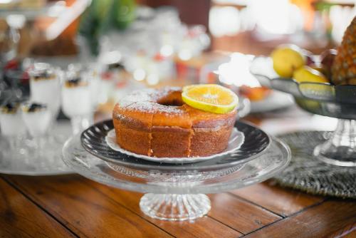 a cake on a glass plate with a lemon on top at Pousada Jardim Monte Verde in Monte Verde