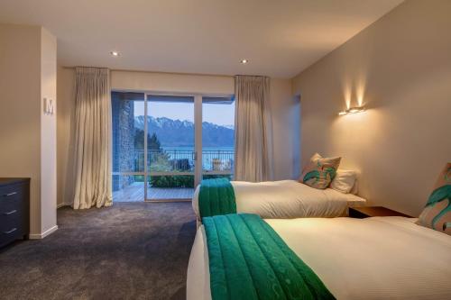 ein Hotelzimmer mit 2 Betten und einem großen Fenster in der Unterkunft Villa Matau- Gas Fire- Lake Views- AC- BBQ in Queenstown